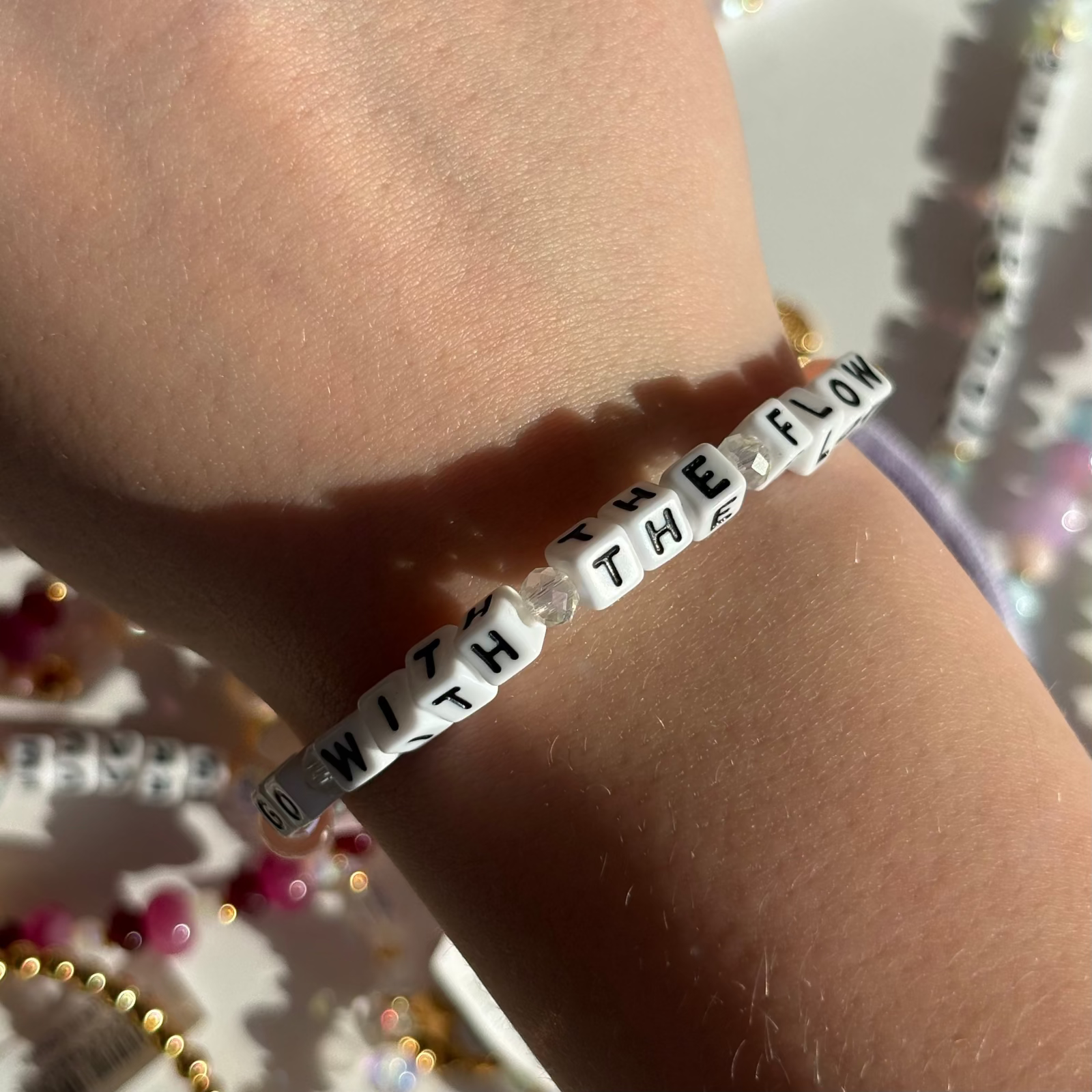 Little Words Project Bracelet with motivational message on wrist against a blurred background