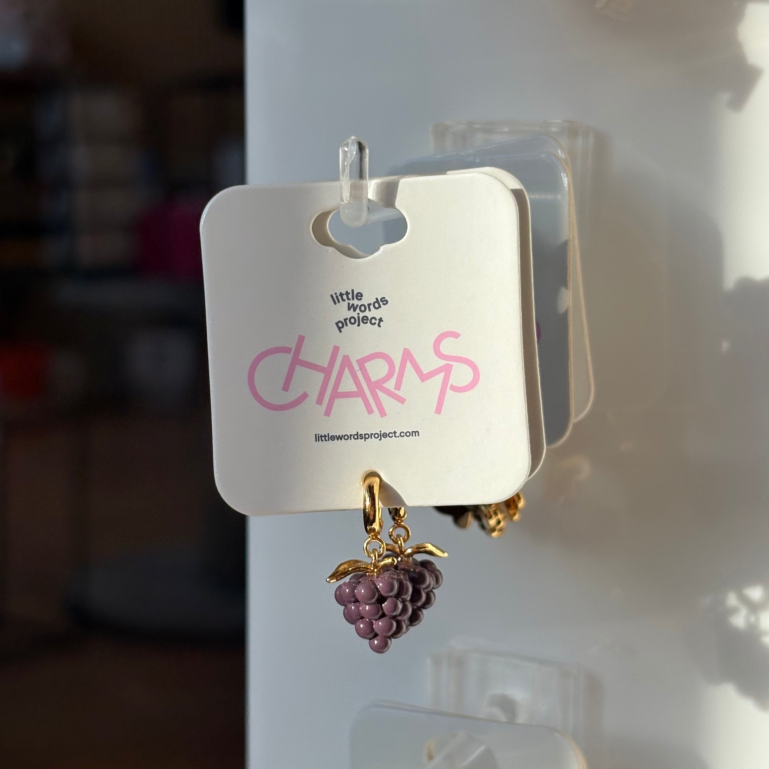 Grape charm on a card with 'little words project' branding