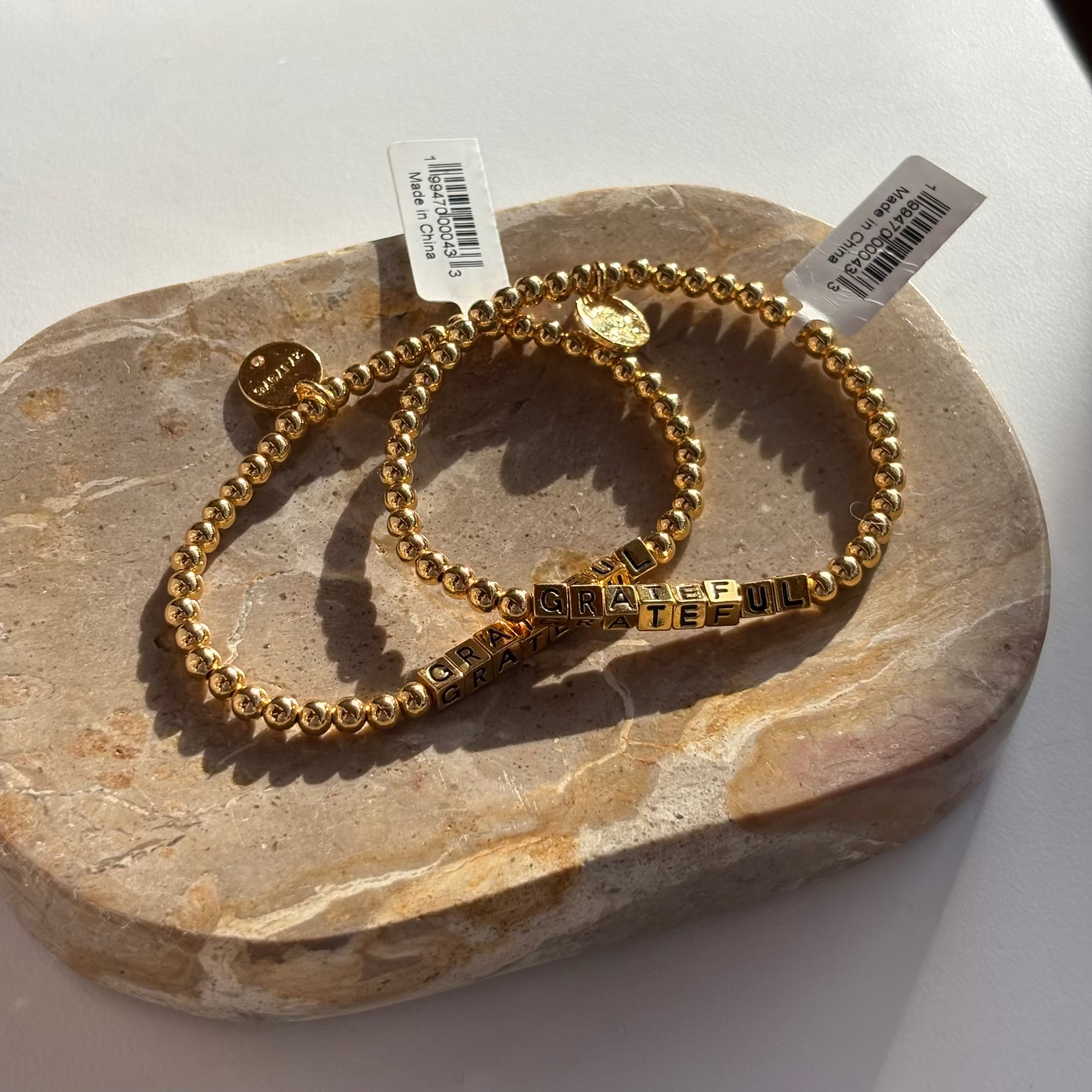 Little Words Project Gold beaded bracelet with engraved text on a stone surface
