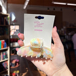 Hand holding a pastel-colored hair clip star charm with a 'little words project' packaging.