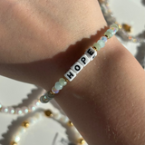 Little Words Project Bracelet with 'HOPE' beads on a wrist against a light background