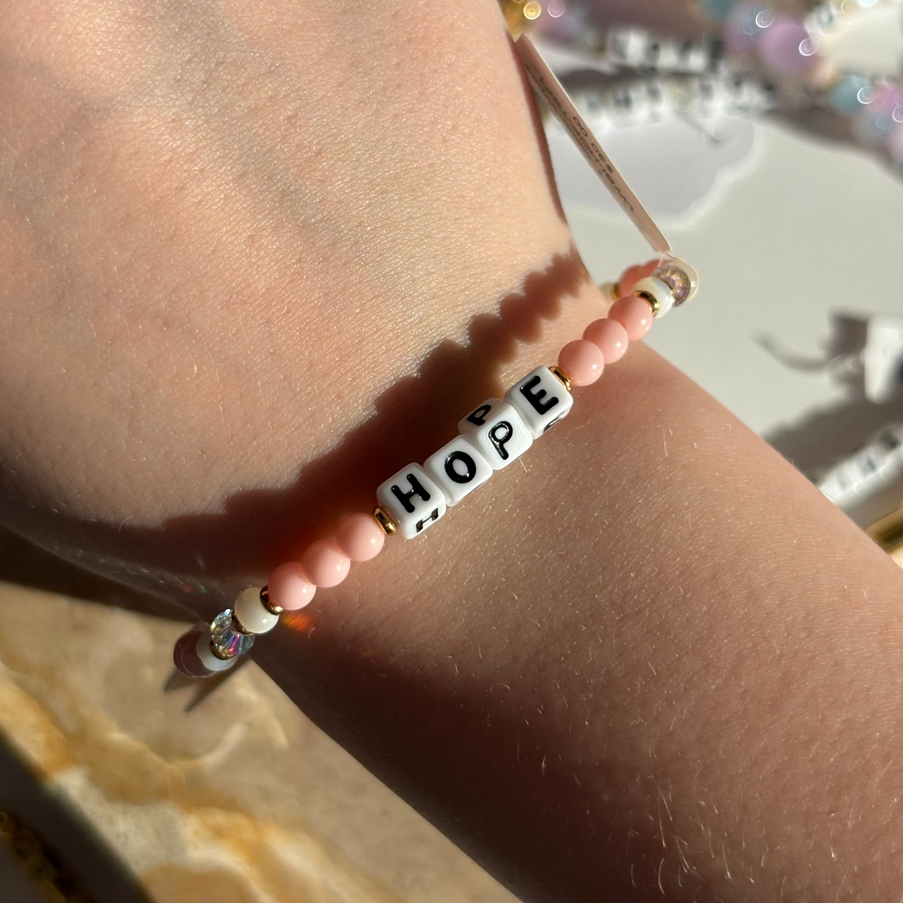 Little words project bracelet with 'HOPE' beads on a wrist, blurred background