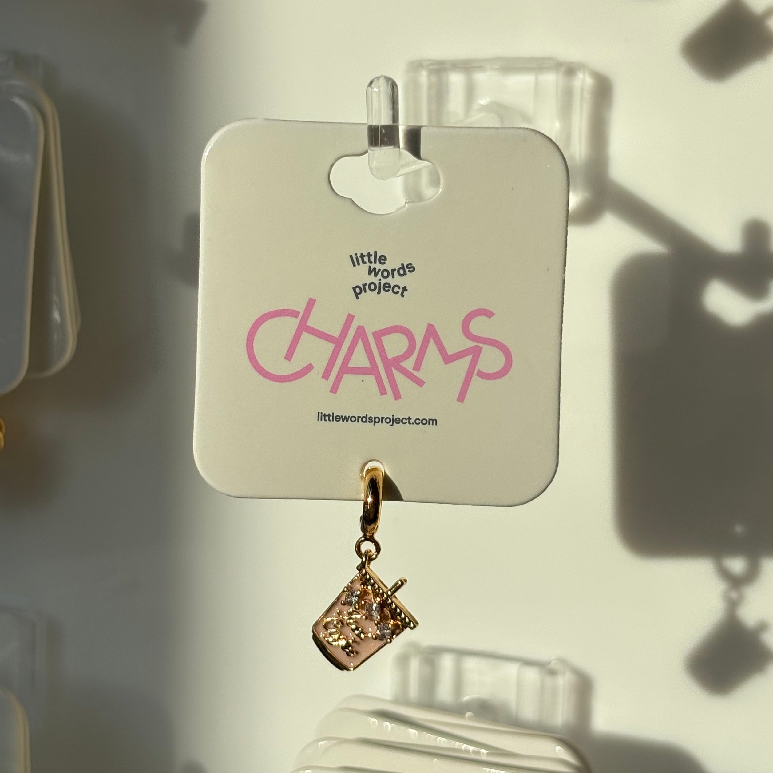 Gold iced coffee charm on a 'little words project' card with pink text