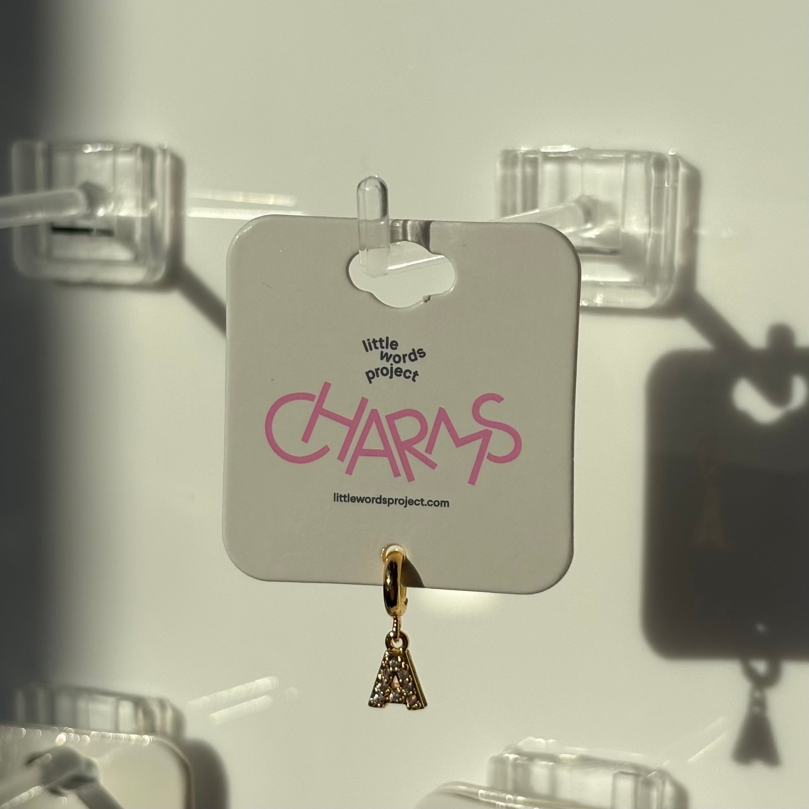 Gold letter 'A' charm on a 'little words project' card against a white background 