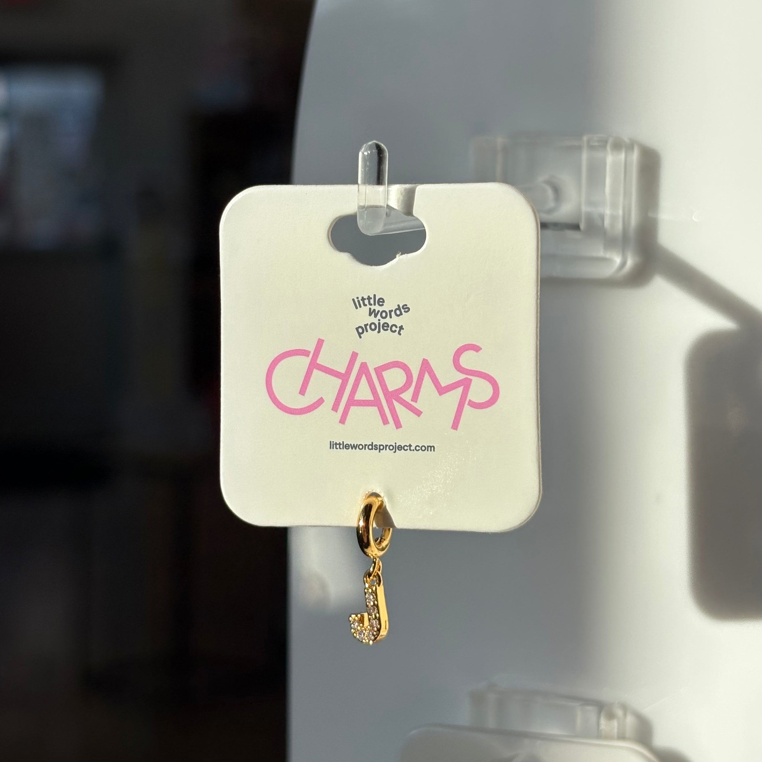 Gold J charm on a 'little words project' card with pink text.