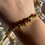 Gold and green louis disney beaded bracelet on a wrist with a blurred background