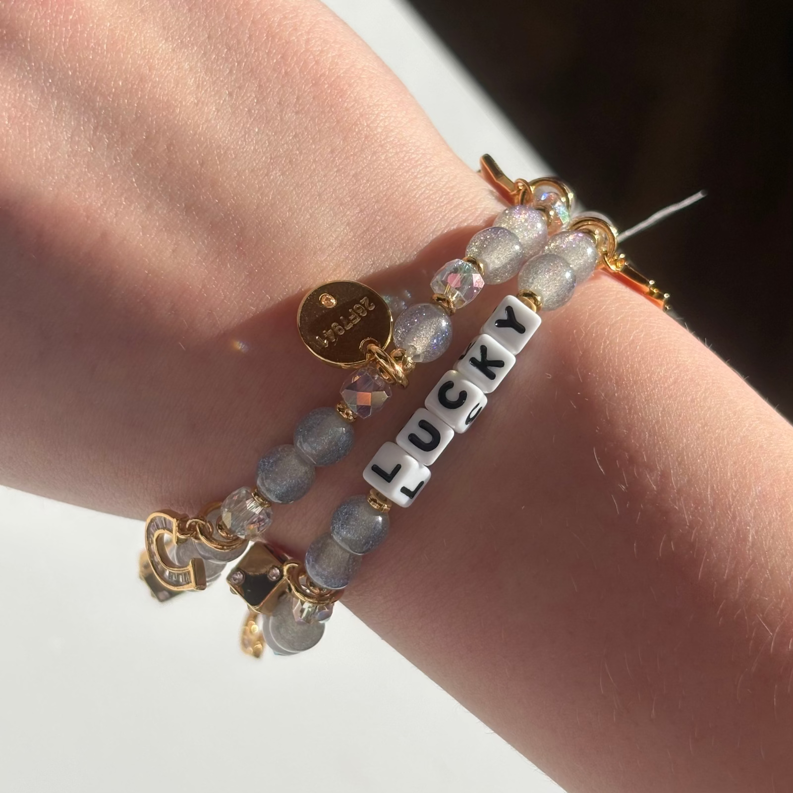 Little Words Project Bracelet with 'LUCKY' charm on a wrist against a neutral background