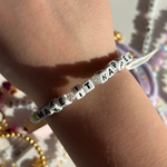 Little Words Project Bracelet with 'MAKE IT HAPPEN' message on wrist with colorful background
