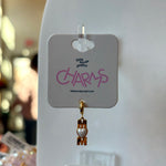 Gold mom charm on a 'little words project' card with blurred background