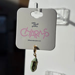 Green two peas charm on a 'Little Words Project' card with a blurred background