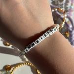 Little Words Project Bracelet with 'SUNKISSED' beads on a wrist against a blurred background