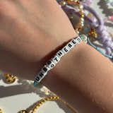 Little Words ProjectBracelet with 'UNBOTHERED' on a wrist with colorful beads in the background