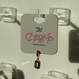 Gold number 0 charm on a 'little words project' card with clear hooks in the background