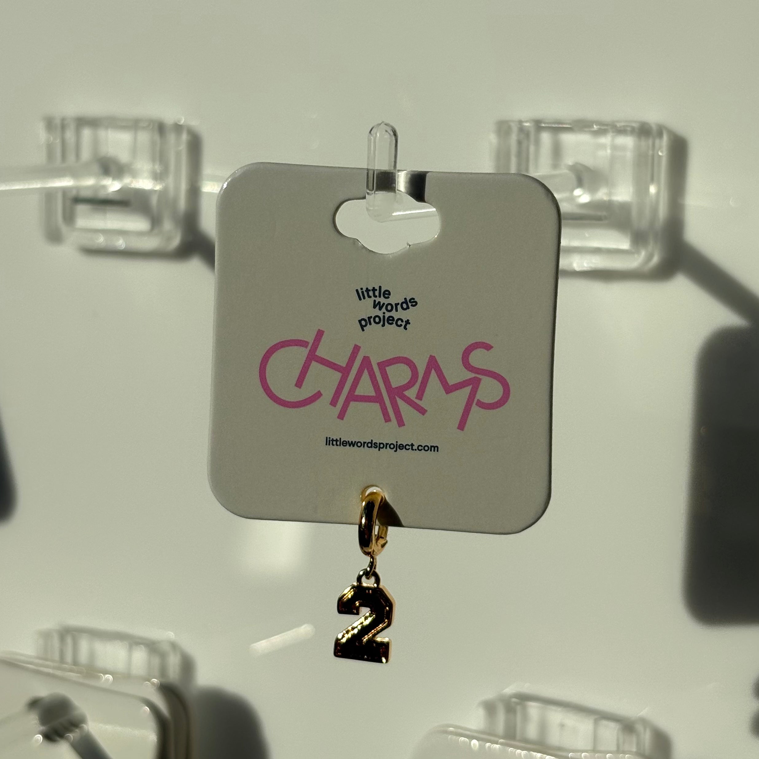 Gold charm with number '2' on a 'CHARMS' branded card against a white background