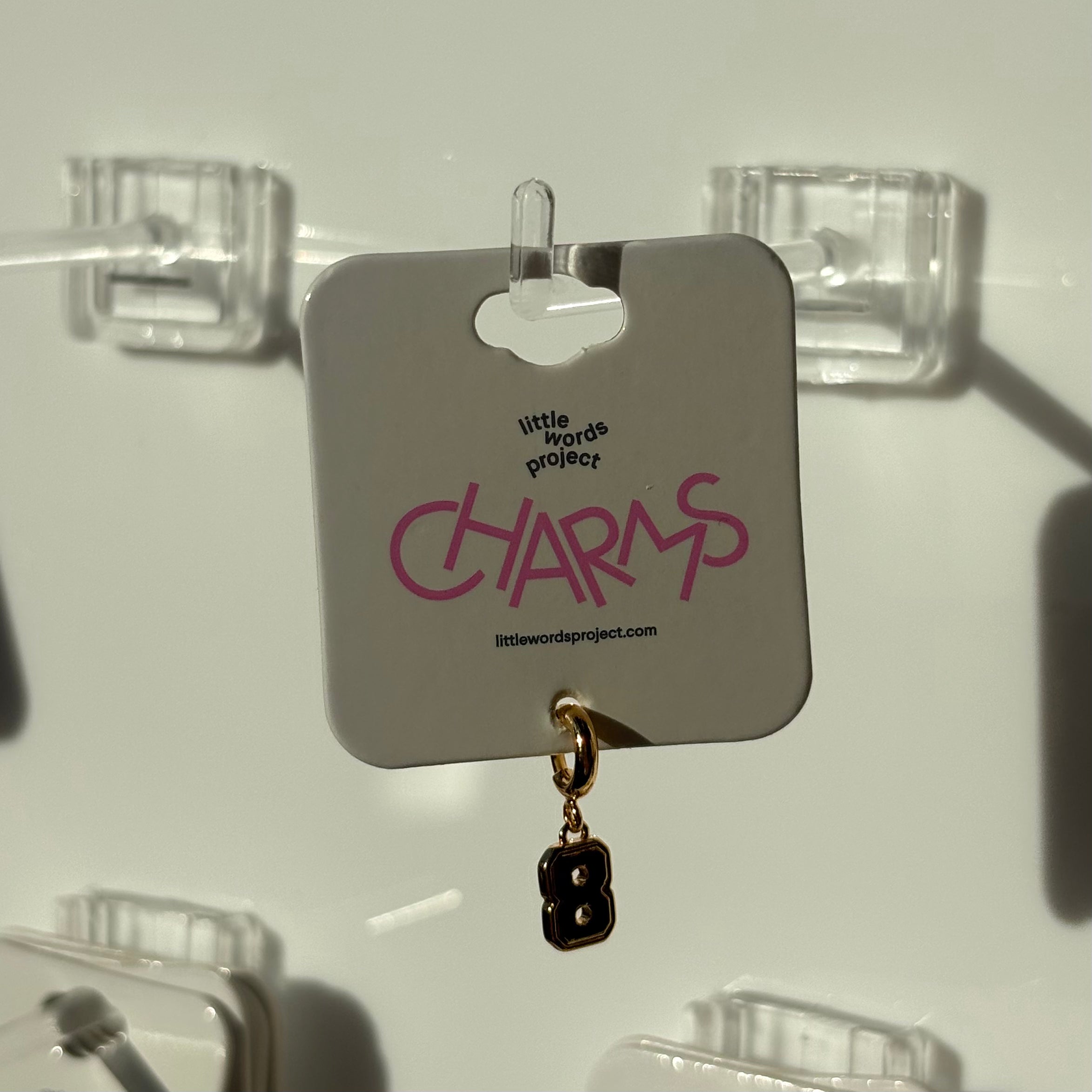 Earring on a display card with 'little words project CHARMS' number 8 branding.