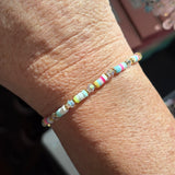 Close-up of a wrist wearing a colorful confetti LWP beaded bracelet with a blurred background.