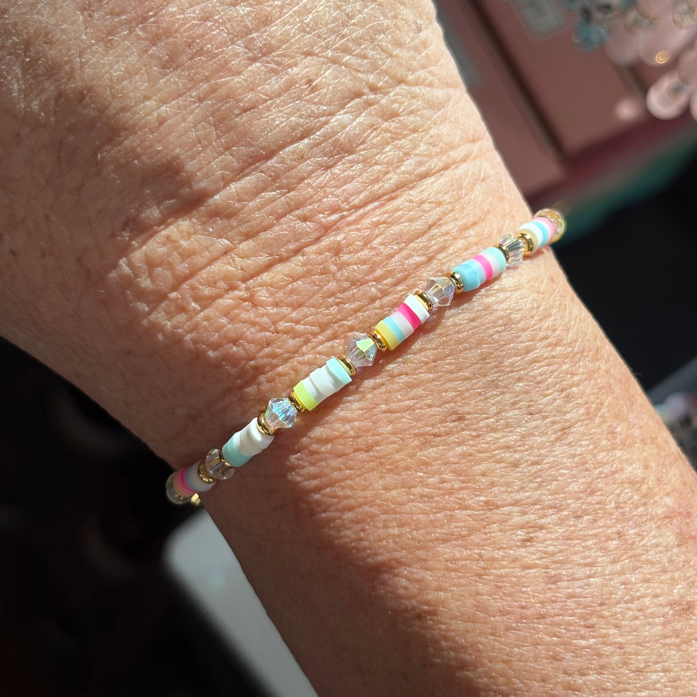 Close-up of a wrist wearing a colorful confetti LWP beaded bracelet with a blurred background.
