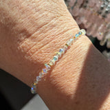 Close-up of a wrist wearing a crystal beaded bracelet with a blurred background
