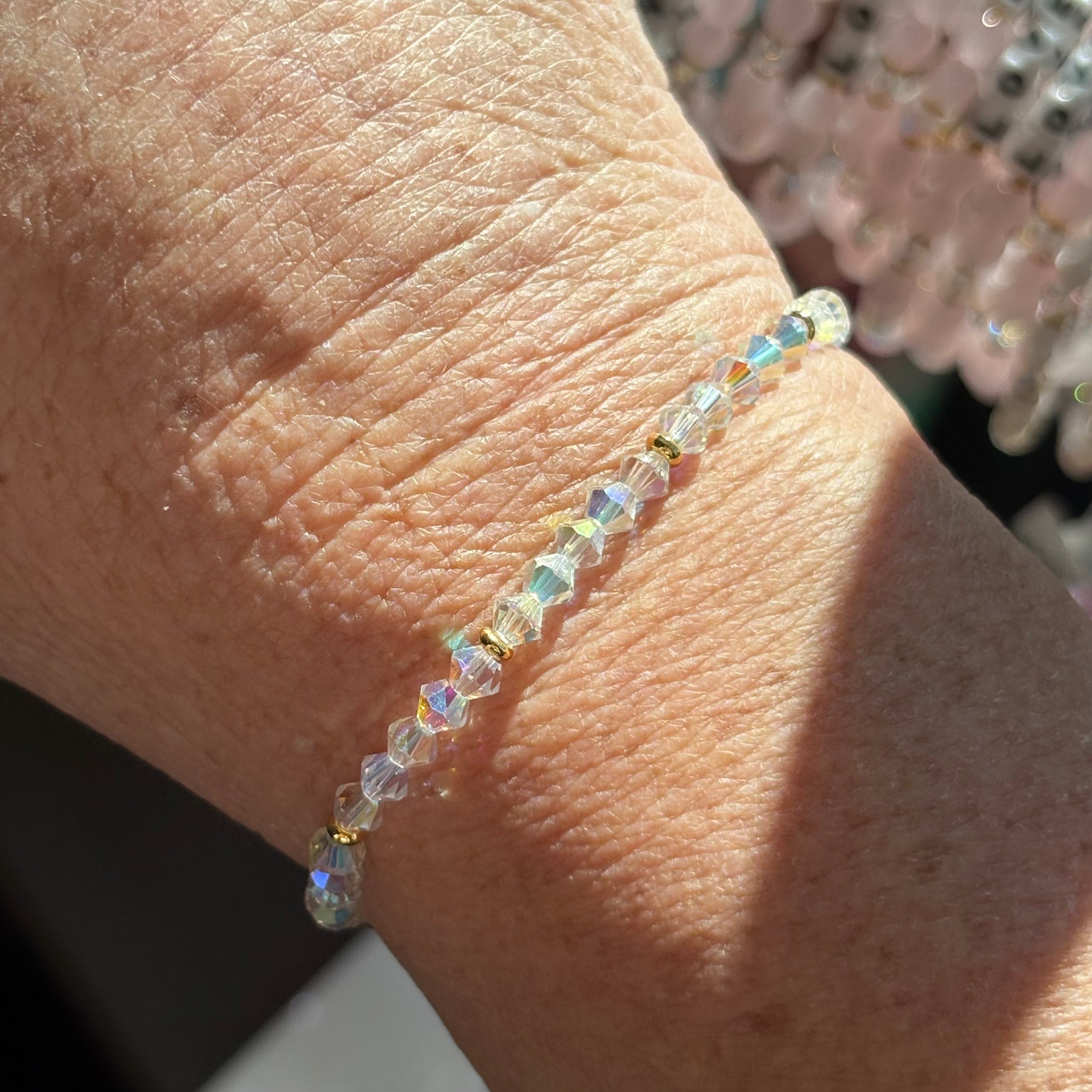 Close-up of a wrist wearing a crystal beaded bracelet with a blurred background