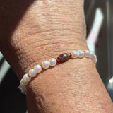 Pearl LWP football beaded bracelet on a wrist with a blurred background