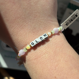 Bracelet with 'GLOW' beads on a wrist, blurred background