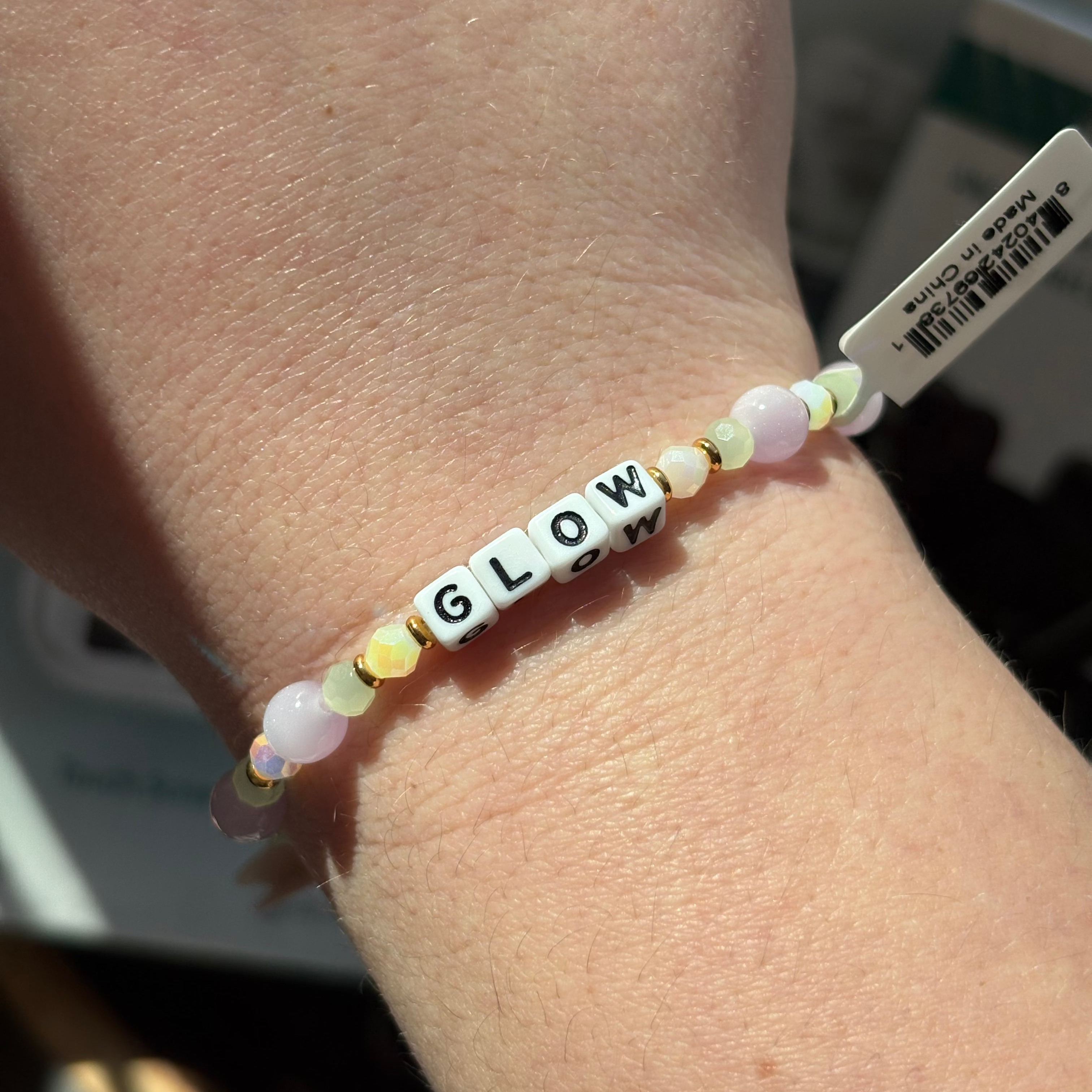 Bracelet with 'GLOW' beads on a wrist, blurred background