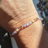 Close-up of a wrist wearing a "heart by the yard" beaded bracelet with a blurred background