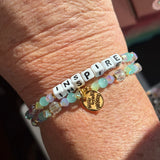 LWP bracelet with 'INSPIRE' beads and a gold charm on a wrist.