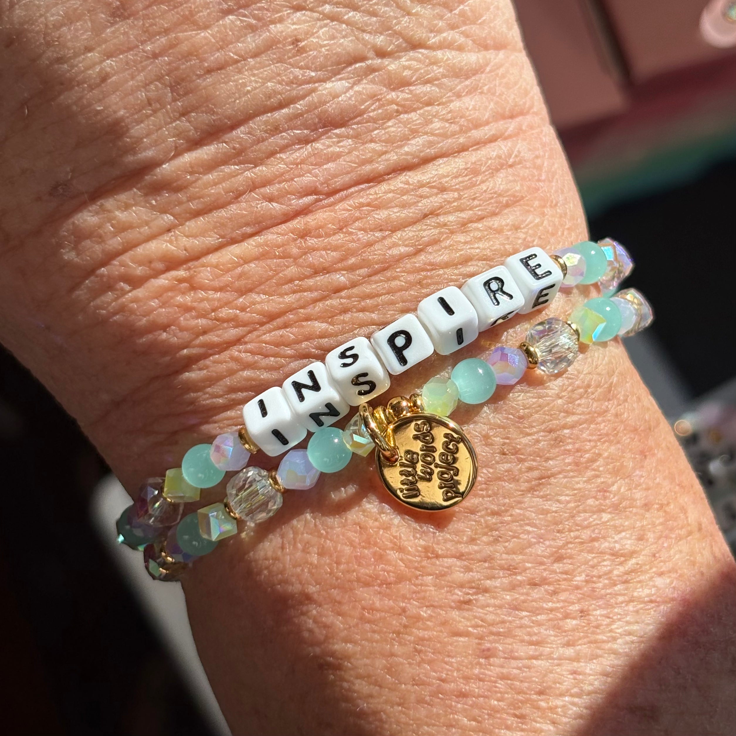 LWP bracelet with 'INSPIRE' beads and a gold charm on a wrist.