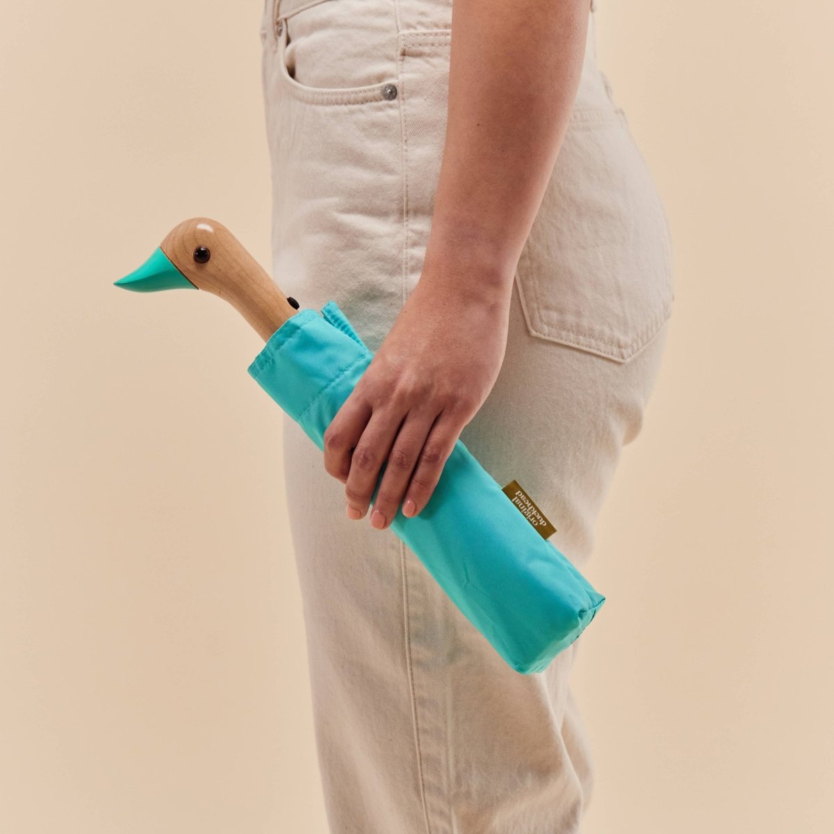 Person holding a blue duckhead against a beige background
