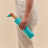 Person holding a blue duckhead against a beige background