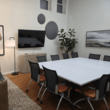 Modern office or meeting room with a white table, chairs, and wall art.