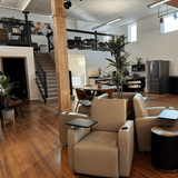 Modern living room with beige recliner chairs, coffee table, and decorative items.