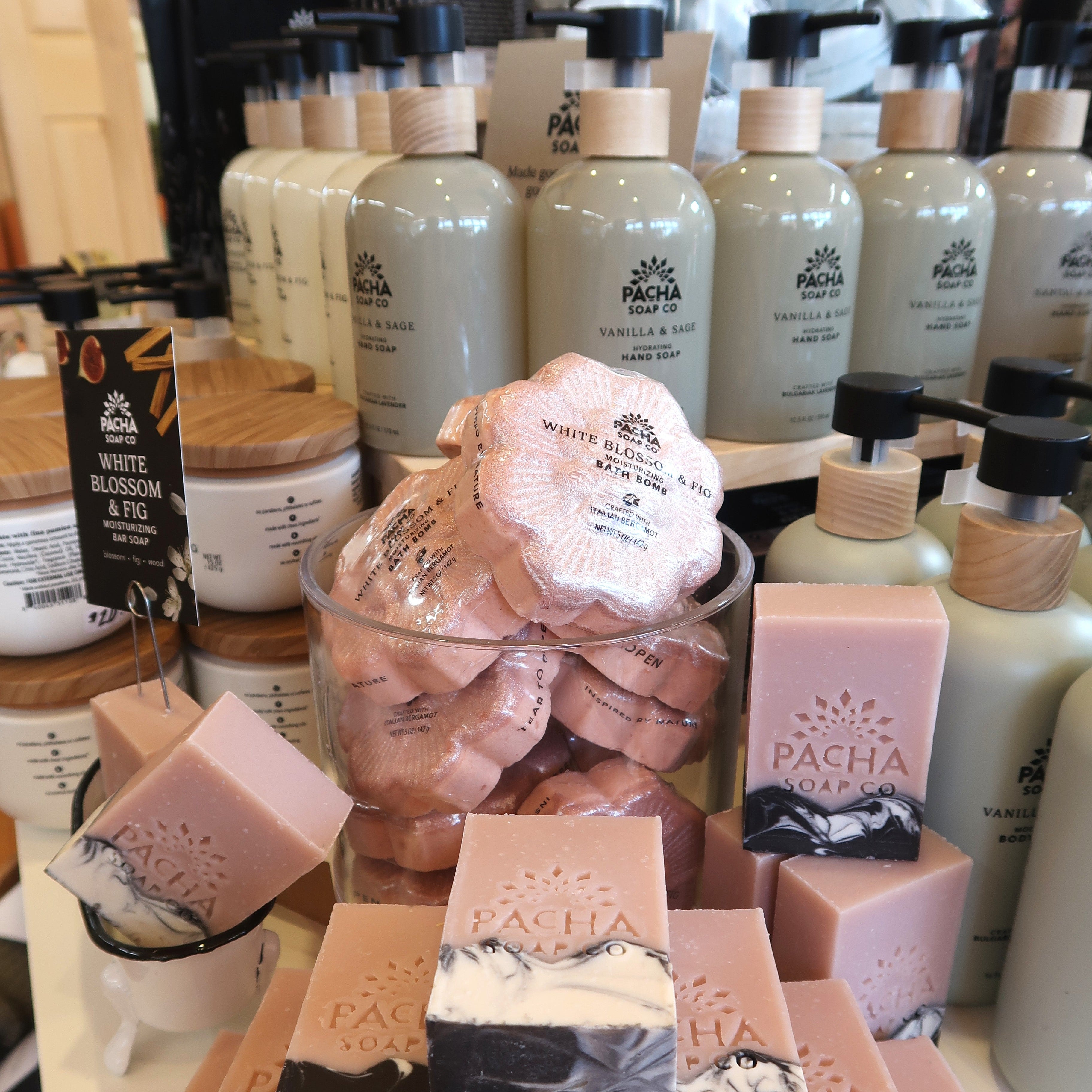 Display of Pacha Soap Co products including soap bars and bottles on a shelf.