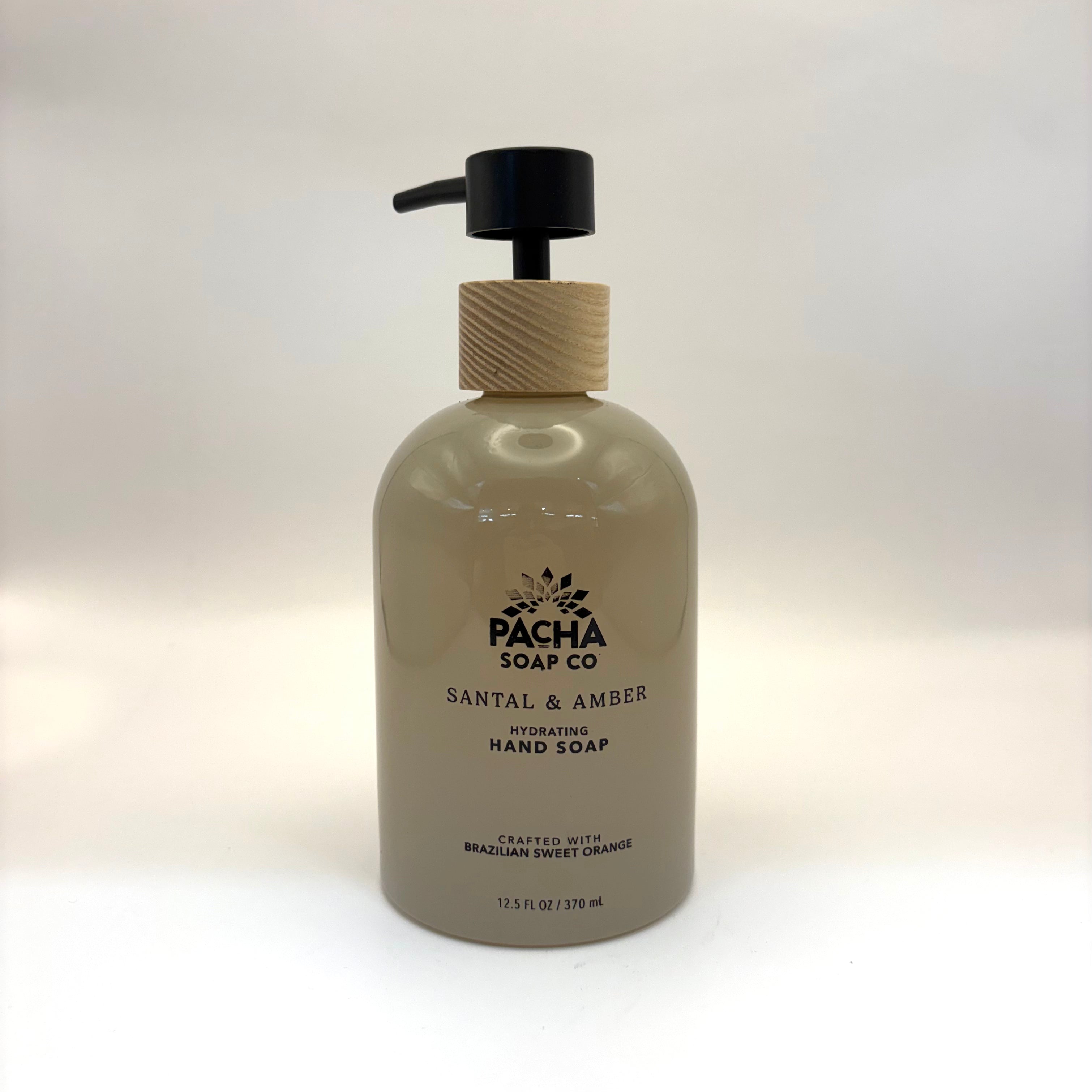 Santal and amber hand soap bottle with wooden pump on a white background