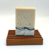 Bar of santal and amber soap with 'Pacha Soap Co' branding on a wooden stand against a white background