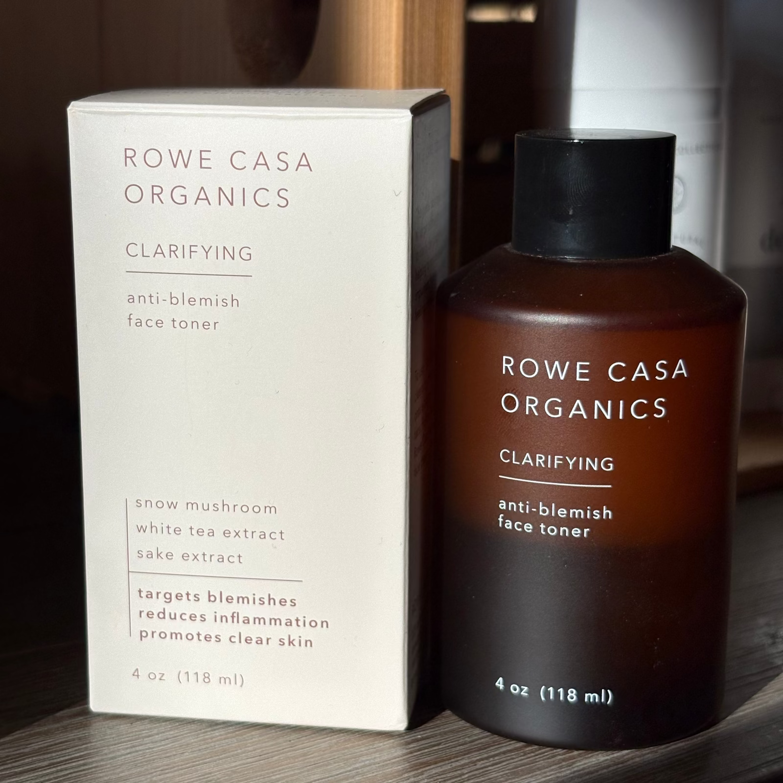 Rowe Casa Organics clarifying anti-blemish face toner bottle and packaging on a wooden surface.