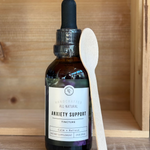 Rowe Casa bottle of all-natural anxiety support tincture with a wooden spoon on a wooden surface