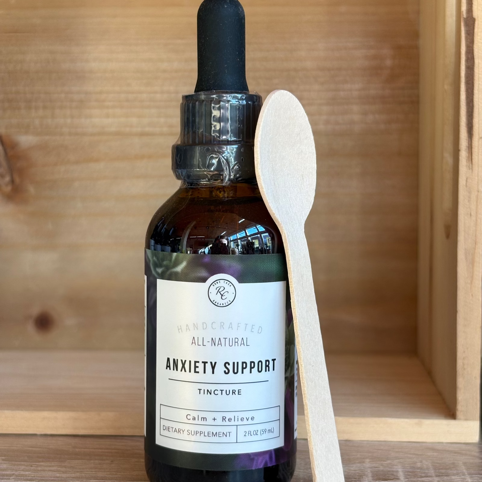 Rowe Casa bottle of all-natural anxiety support tincture with a wooden spoon on a wooden surface
