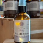 Baby bottom spray bottle on a wooden surface with other similar bottles in the background.