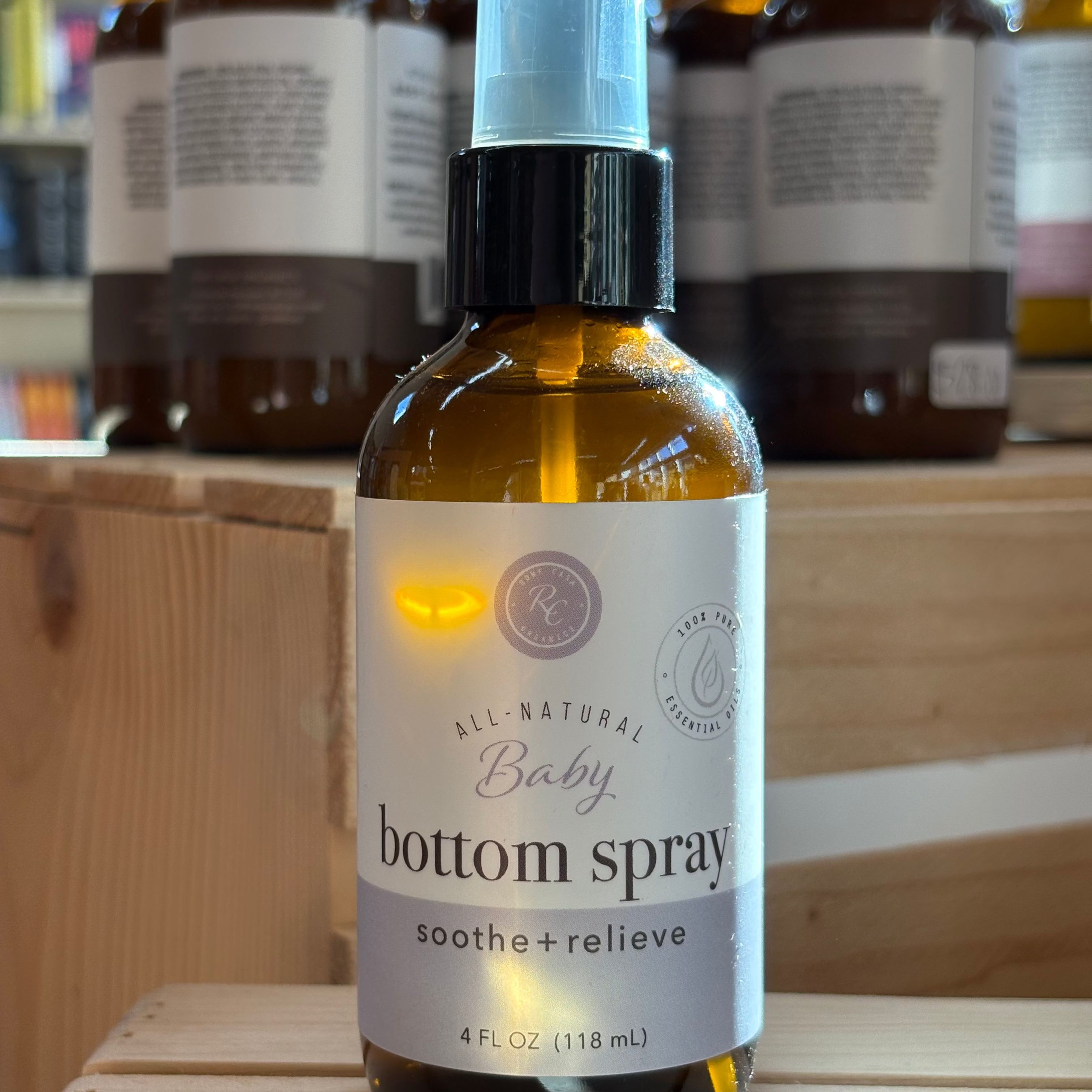 Baby bottom spray bottle on a wooden surface with other similar bottles in the background.