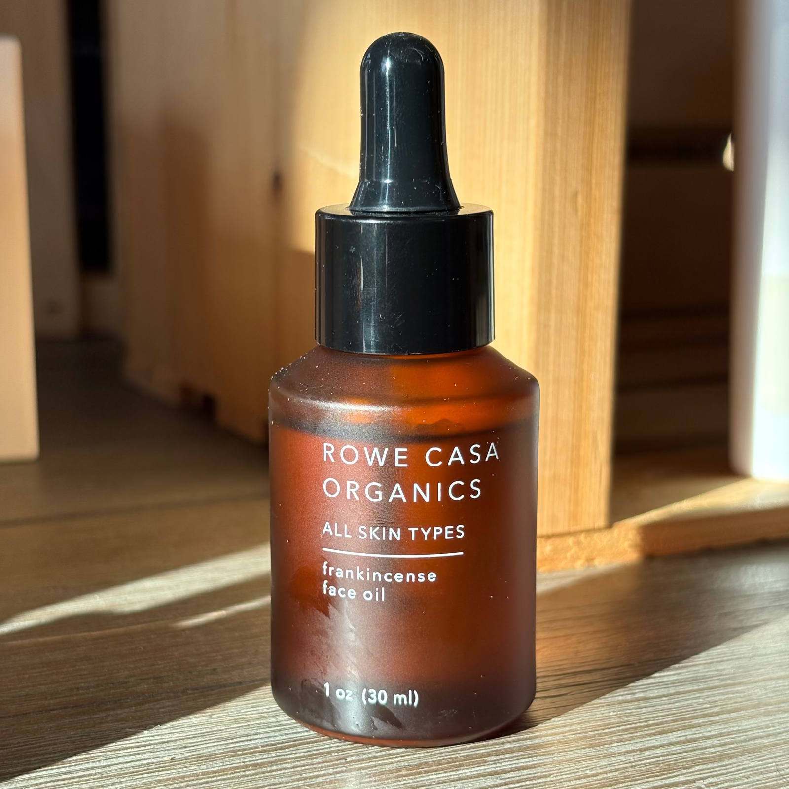 Rowe Casa Organics frankincense face oil bottle on a wooden surface