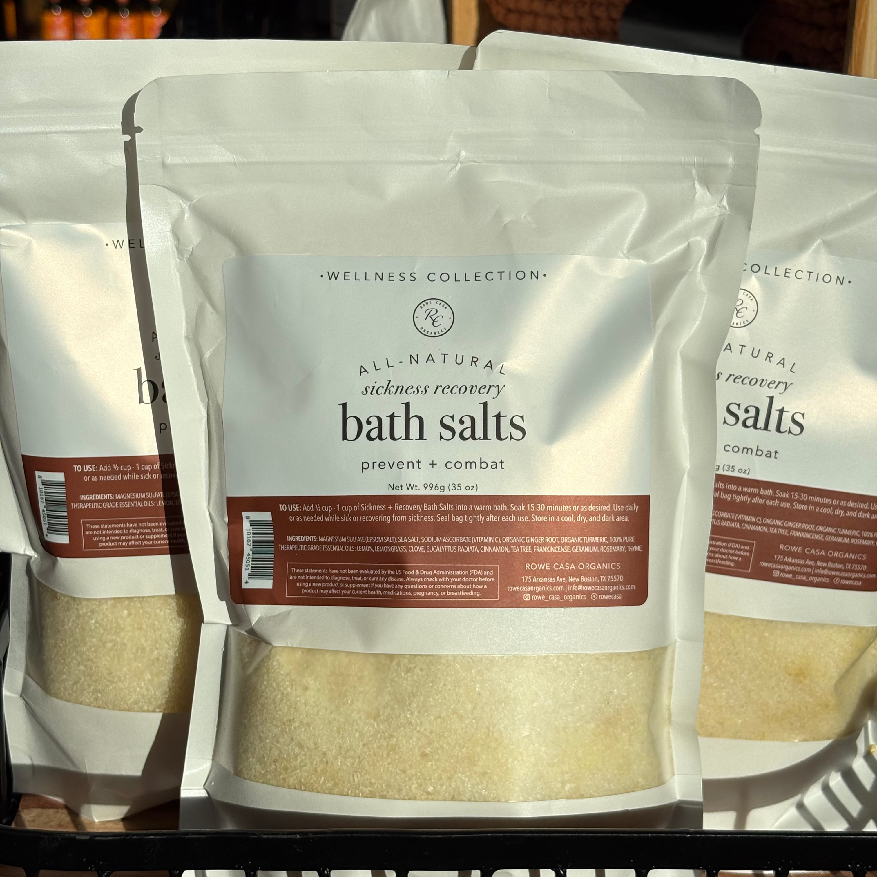 Packages of All-Natural Rowe Casa Sickness Recovery bath salts on a shelf.