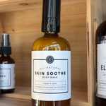 Bottle of 'Skin Soothe' body wash on a wooden shelf with other products.