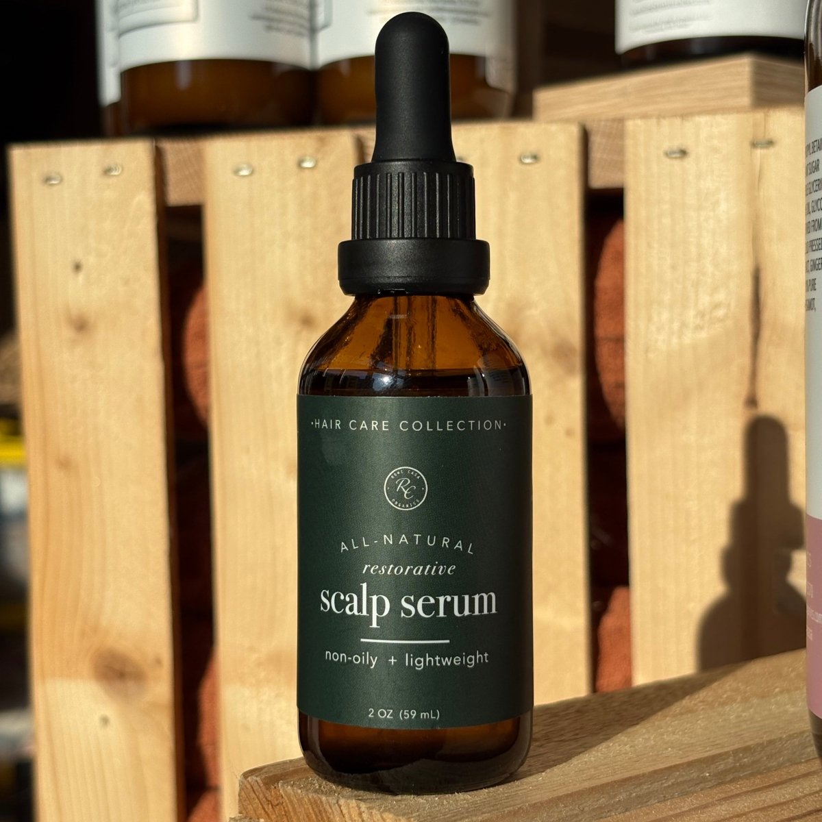 Bottle of scalp serum on a wooden surface with other bottles in the background
