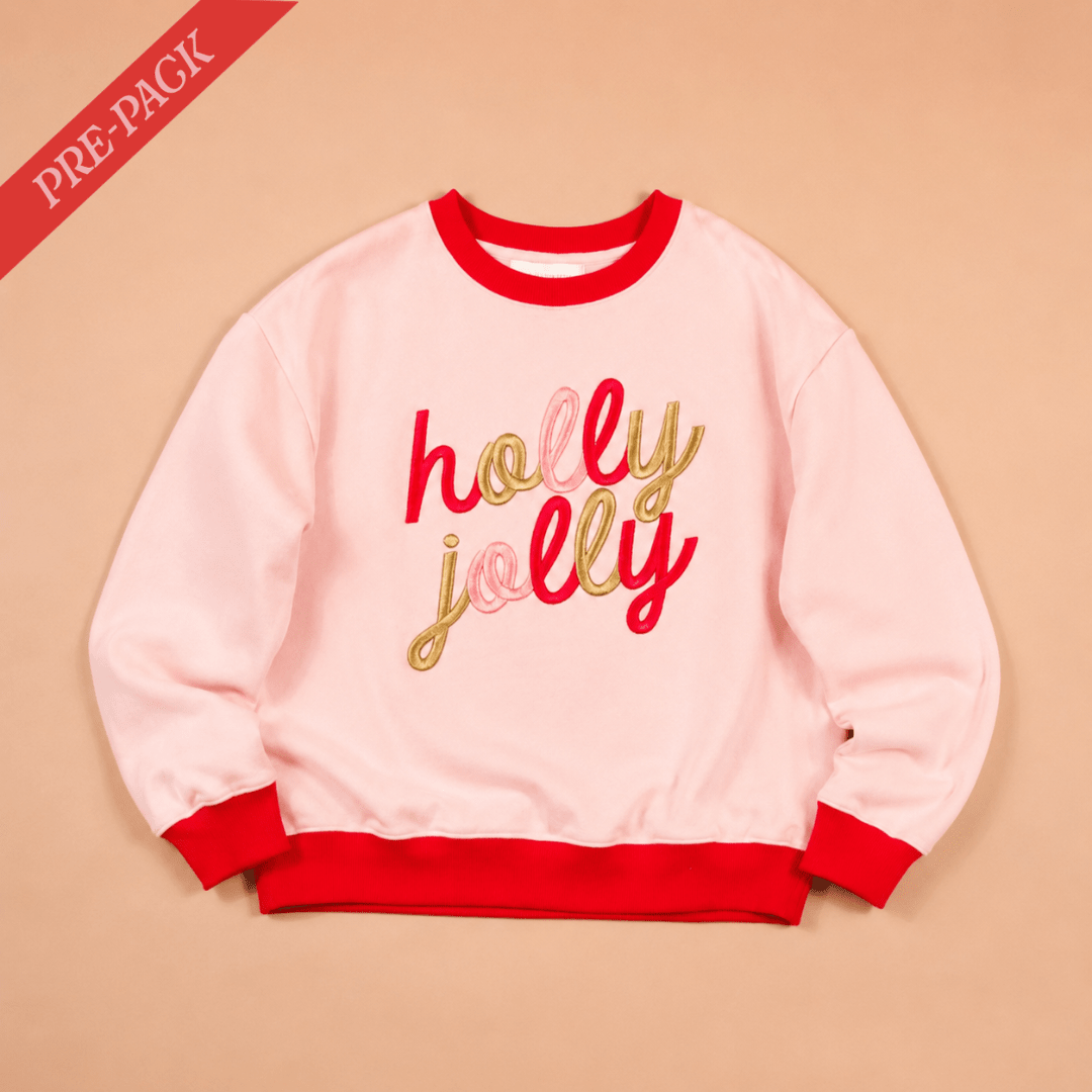 Pink sweatshirt with 'holly jolly' text on a beige background