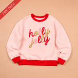Pink sweatshirt with 'holly jolly' text on a beige background