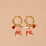 Gold hoop earrings with wine glass and bow designs on a beige background