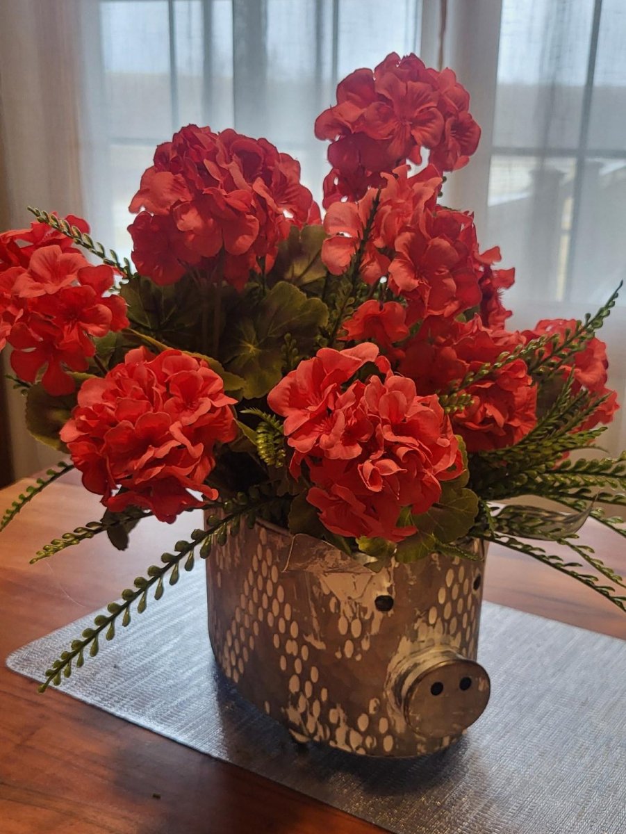 Decorative pot with red flowers on a wooden table