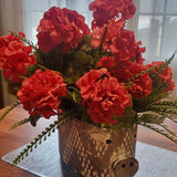 Decorative pot with red flowers on a wooden table